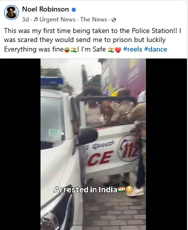 A person named Noel Robinson exits a police vehicle on a street in India, surrounded by officers. The mood is lighthearted, with the caption "Arrested in India" humorously displayed.